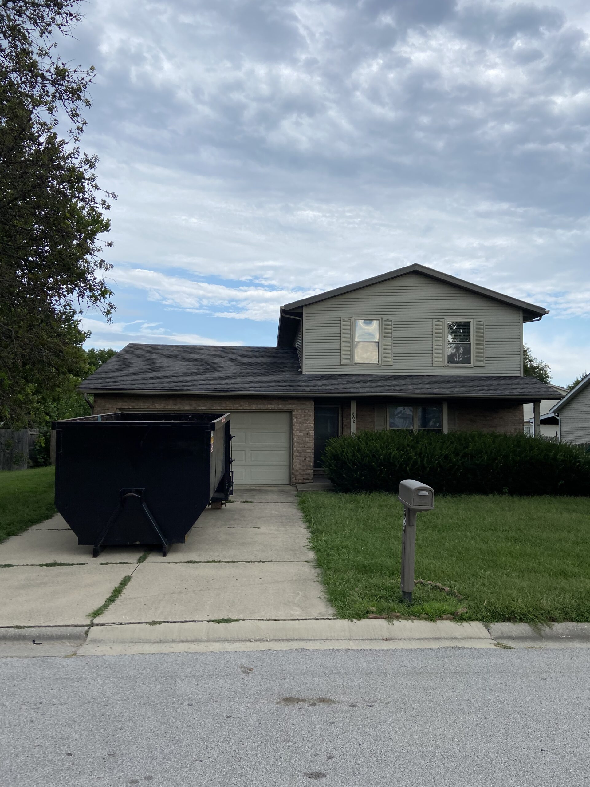 IMG_2639 Large black dumpster parked in a suburban driveway.