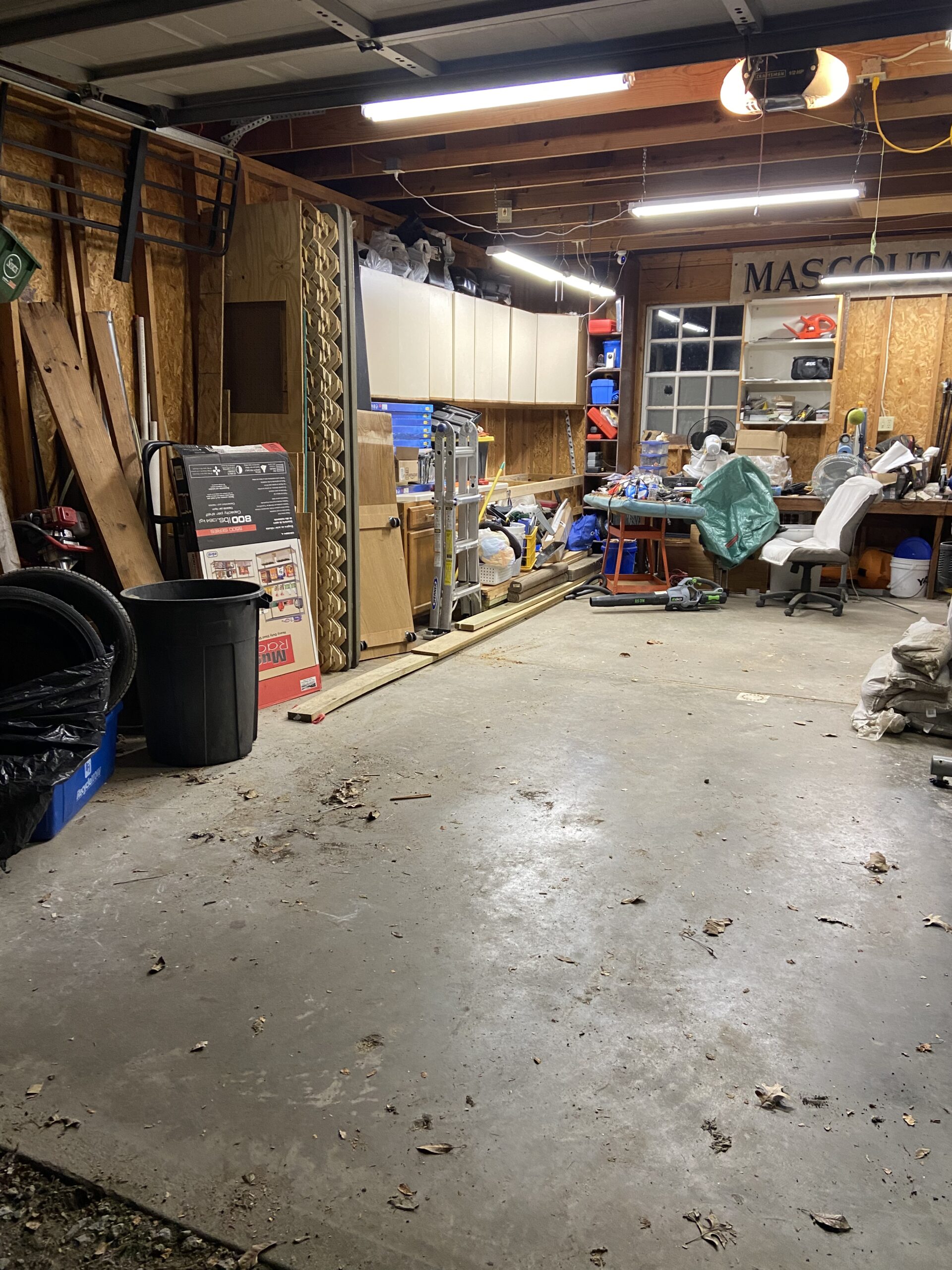 IMG_3293 Interior view of a cluttered garage with wood and tools.