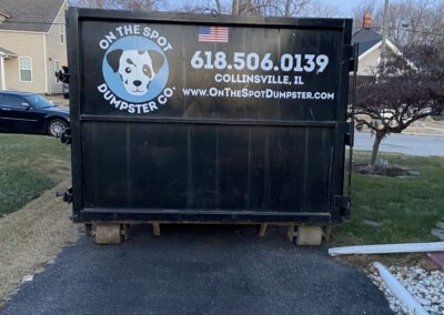 Rear of a black dumpster with "On The Spot Dumpster Co." logo.